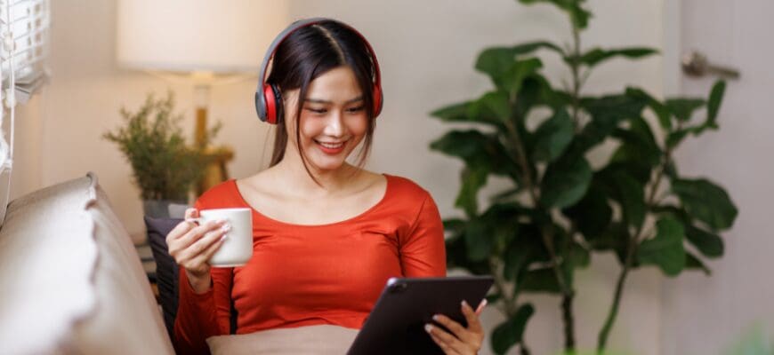 A woman lounging on a living room couch, reading a tablet